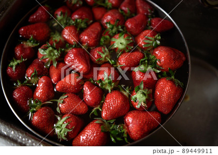 Juicy ripe red strawberries are washed in a steel bowl full of water. 89449911