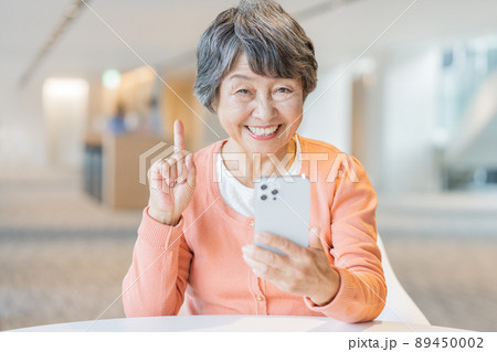 スマホを手に笑うシニア女性のポートレート　撮影協力「LINK FOREST] 89450002