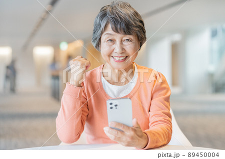 スマホを手に笑うシニア女性のポートレート　撮影協力「LINK FOREST] 89450004