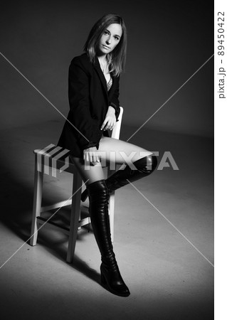 woman posing sitting on a chair in jacket and lingerie, black and white photo 89450422