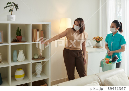 Woman Asking Cleaner to Dust Shelves Woman Asking Cleaner to Dust Shelves 89451367
