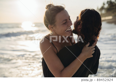 On the ocean, a man picked up in his beloved's arms they both laugh 89452924