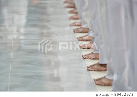 Asian men feet are standing in a row with all white trousers. 89452973