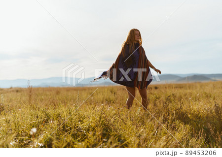 whirling in an ethno cape of a long-haired girl among the steppe grass against the backdrop of the hills whirling in an ethno cape of a long-haired girl among the steppe grass against the backdrop of the hills 89453206