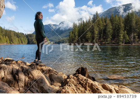 Adventurous Caucasian Woman on the rocks by the water in Canadian Nature Landscape. Adventurous Caucasian Woman on the rocks by the water in Canadian Nature Landscape. 89453739