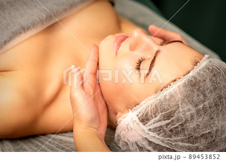 Facial massage. Hands of a masseur massaging neck of a young caucasian woman in a spa salon, the concept of health massage 89453852