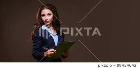 A young girl holds a folder with documents on a brown background. 89454642