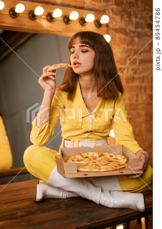 Young woman sitting eating pizza Young woman sitting eating pizza 89454786