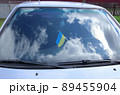 The Ukrainian flag is affixed to the windshield of a car. Reflected sky with clouds. 89455904