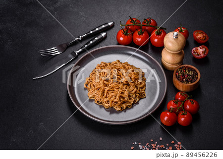 Buckwheat flour noodles with sauce, sesame, herbs and spices on a dark concrete background Buckwheat flour noodles with sauce, sesame, herbs and spices on a dark concrete background 89456226
