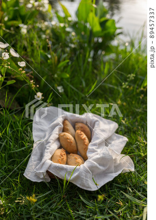 Composition of white flour buns in basket with white white cloth napkin on the green grass. High quality photo 89457337