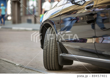 Close up detail part of car wheel with new black rubber tire protector on light blurred copy space background. Transportation, safety, reliability, modern design concept. 89457401