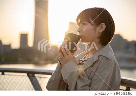 屋外でコーヒーを飲みながら物思いにふける女性の様子 89458166