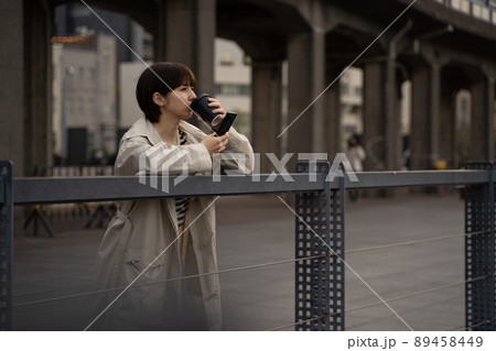 珈琲を飲みながらスマホを使う女性の様子 89458449