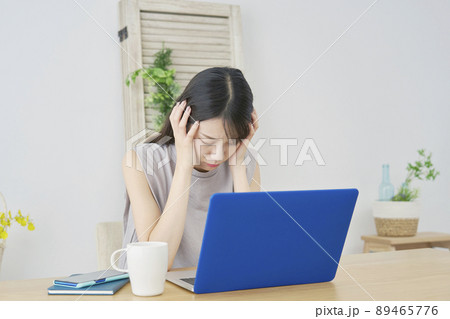 女性　ノートパソコン　頭を抱ええる　リビング 89465776