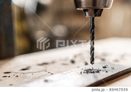 Drilling hole in steel plank in workshop 89467039