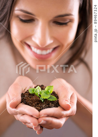 She knows her investment will grow. Cropped shot of a beautiful young woman holding a tiny plant in her hands. 89467324