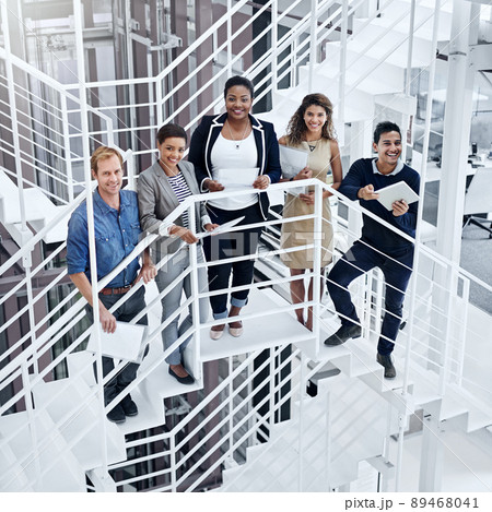The team that makes success happen. Portrait of a group of smiling coworkers standing on stairs in a modern office. 89468041
