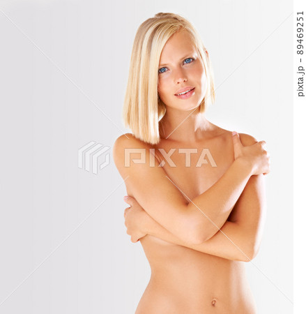 Comfortable in my own skin. Stunnig young woman isolated on grey with ther arms covering her nude breasts. Comfortable in my own skin. Stunnig young woman isolated on grey with ther arms covering her nude breasts. 89469251