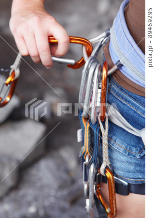 Attaching herself to the rope. A rock climbers hook with an assortment of clips attached to it. Attaching herself to the rope. A rock climbers hook with an assortment of clips attached to it. 89469295