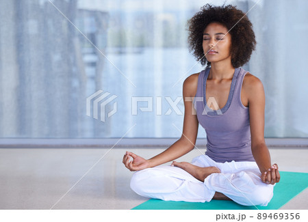 Finding inner peace. Shot of an attractive young woman meditating on an exercise mat. 89469356