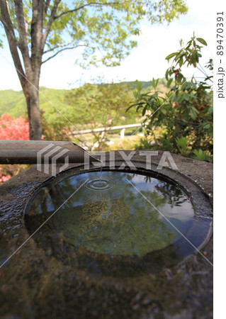 蹲、つくばいのアップ、竹筒から滴り落ちる水が手水鉢の表面に輪紋を作り、水鏡に空や樹々の葉が写る、縦 蹲、つくばいのアップ、竹筒から滴り落ちる水が手水鉢の表面に輪紋を作り、水鏡に空や樹々の葉が写る、縦 89470391