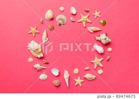 Summer time concept on colored background. Seashells from ocean shore in the shape of frame separated with space for text top view Summer time concept on colored background. Seashells from ocean shore in the shape of frame separated with space for text top view 89474675