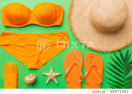 Woman swimwear and beach accessories flat lay top view on colored background Summer travel concept. bikini swimsuit, straw hat and seasheels. Copy space Top view 89475481