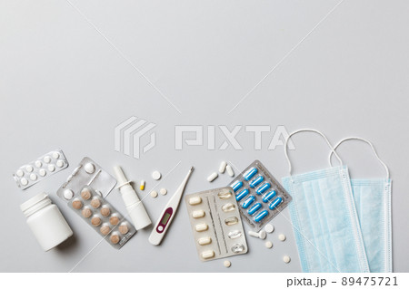 Protective face masks or surgical masks, medicine pills and thermometer on table background. Coronavirus disease. Corona virus concept. Space for text Protective face masks or surgical masks, medicine pills and thermometer on table background. Coronavirus disease. Corona virus concept. Space for text 89475721