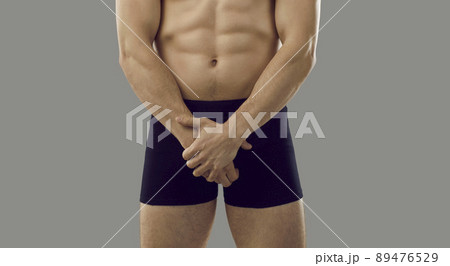 Man who has problems with erection standing on grey background and covering his crotch 89476529