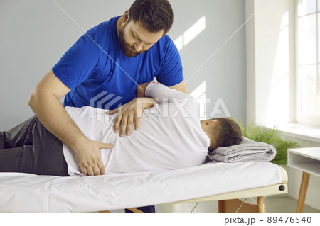 Male physiotherapist help client with backache Male physiotherapist help client with backache 89476540