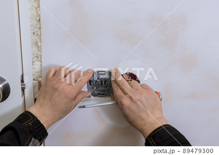 Closeup of electrician hands installing wall socket 89479300