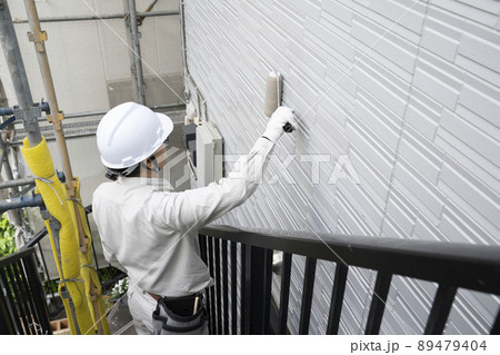 刷毛で戸建て住宅の外壁を塗る塗装職人 89479404
