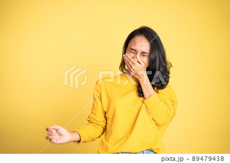 woman laughing hard cover her mouth over yellow background 89479438