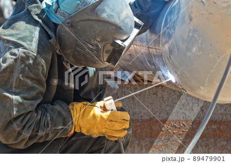 A welder in protective clothing performs the welding of the n element of the process pipeline 89479901