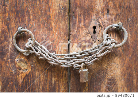 Old rusted padlock, rusted chain, and keyhole on a closed wooden aged grunge door 89480071