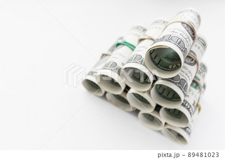 American one hundred dollar bills rolled and stacked in a pyramid. Light background, closeup, selective focus American one hundred dollar bills rolled and stacked in a pyramid. Light background, closeup, selective focus 89481023