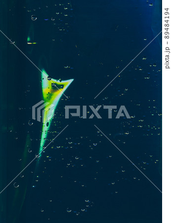 Water drop texture. Light flare overlay. Wet aquarium glass. Clear liquid bubbles yellow green color glow scratches on dark blue window abstract background. Water drop texture. Light flare overlay. Wet aquarium glass. Clear liquid bubbles yellow green color glow scratches on dark blue window abstract background. 89484194