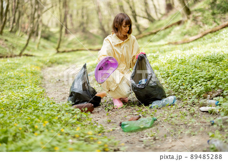 Woman collecting scattered plastic garbage in the woods Woman collecting scattered plastic garbage in the woods 89485288