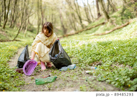 Woman collecting scattered plastic garbage in the woods 89485293