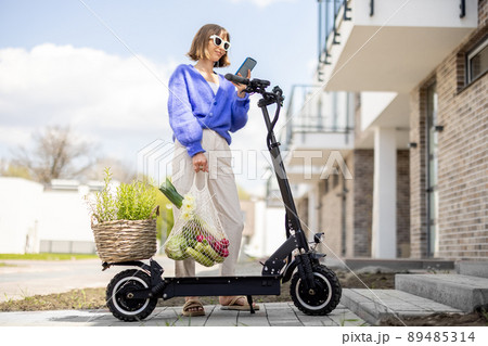 Woman going home with fresh vegetables on electrical scooter Woman going home with fresh vegetables on electrical scooter 89485314