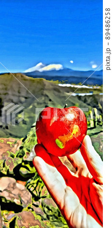 A ripe apple on the fingers of one hand with the landscape in the background. 89486258