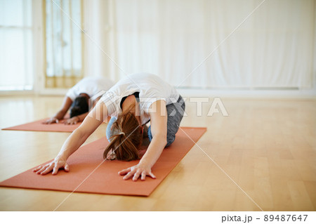 Stretching away the stress. Shot of two women doing yoga together in a studio. 89487647