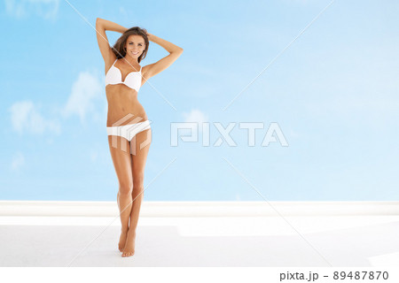 Summer here I come. Full length portrait of a young woman posing in white underwear with a blue sky in the background. 89487870
