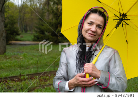 Senior Mental Health well-being, how to Improve Cognition and Emotion. Mental health of older adults. Happy senor woman in yellow raincoat enjoying life and walking in the park 89487991
