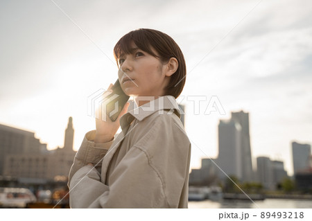 スマホを手に振り向く女性 89493218