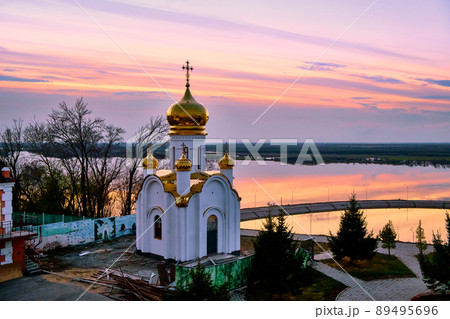 Orthodox church on the territory of the Zaimka tourist complex against the background of a bright sunset over the Ussuri River near the city of Khabarovsk. Russia. Orthodox church on the territory of the Zaimka tourist complex against the background of a bright sunset over the Ussuri River near the city of Khabarovsk. Russia. 89495696
