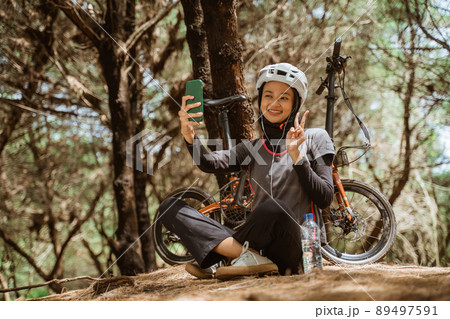 veiled girl smiling wearing earphones while selfie using cellphone veiled girl smiling wearing earphones while selfie using cellphone 89497591