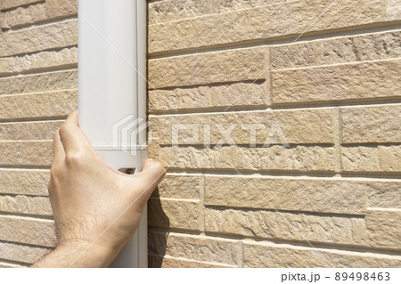 エアコンのホースカバーを確認する男性の手 89498463