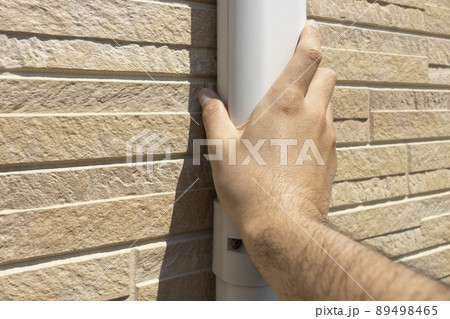 エアコンのホースカバーを確認する男性の手 89498465